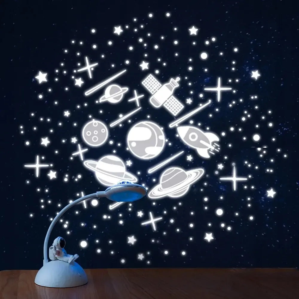 LED naktinis šviestuvas-projektorius su astronauto motyvu, šviečia švelnia šviesa vaikų kambaryje.