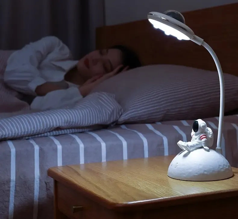 LED naktinis šviestuvas-projektorius su astronauto motyvu, šviečia švelnia šviesa vaikų miego kambaryje.
