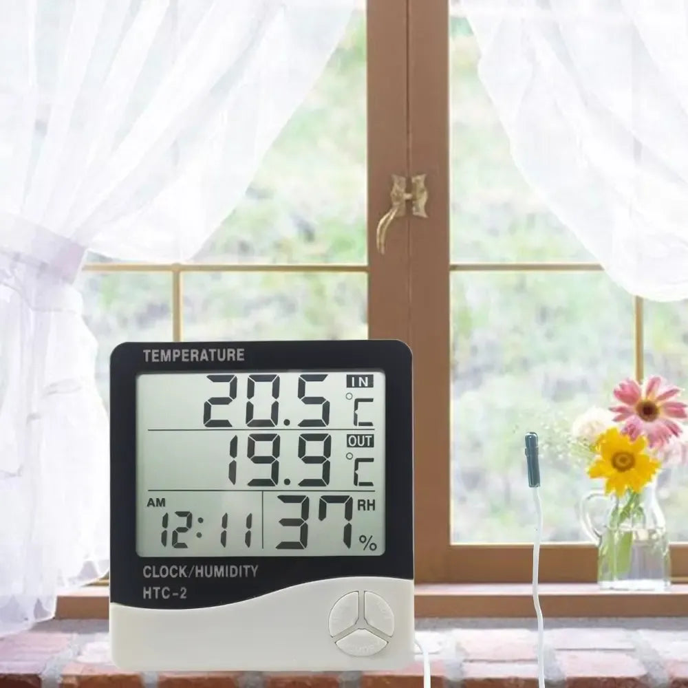 Skaitmeninė meteorologinė stotelė su temperatūros ir drėgmės matuokliu, matosi ekranas ir jutikliai.